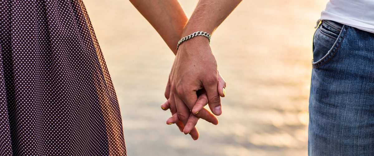 Happy couple holding hands in the sunset