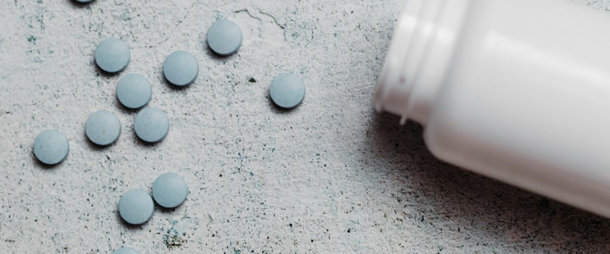 Blue pills and canister on concrete background