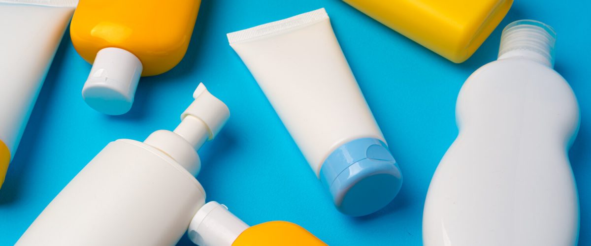 Bottles of sunscreen cream on blue background with copy space