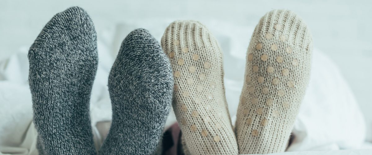 cropped shot of couple in warm woolen socks lying in bed together at home