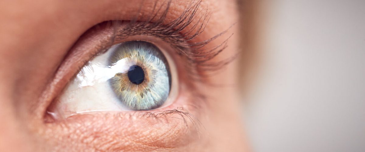 Extreme Close Up Of Eye Of Woman Against White Studio Background