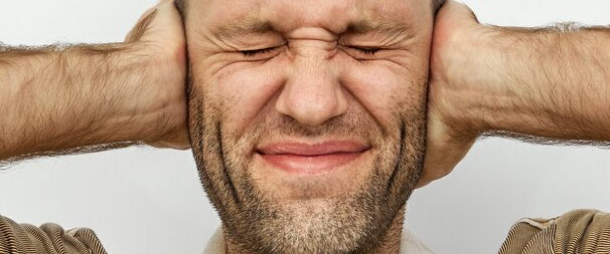 Man with eyes and ears tightly closed with hands