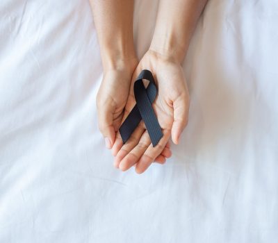 Melanoma and skin cancer, Vaccine injury awareness month and rest in peace concepts. Man holding black Ribbon on white bed background