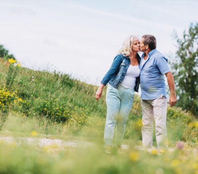 Old couple kissing on a walk. Elderly people retirement activities.
