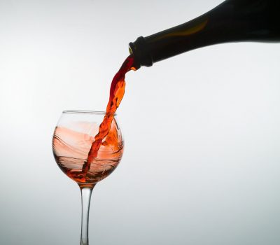 Red wine fills an empty wine glass on a white background