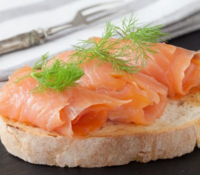 Smoked salmon with fresh dill on bread slice, in natural light, authentic food.