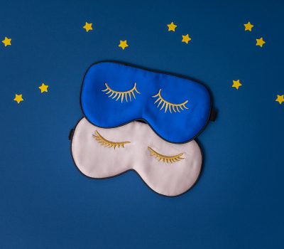 Two sleeping masks and paper stars on blue background, copy space, flat lay, top view