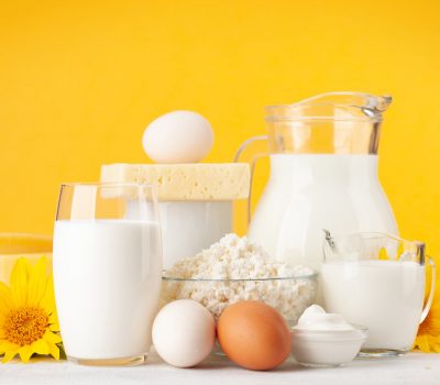 Various dairy products. Milk, cheese, cottage, sour cream. In front of yellow background